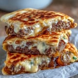 Overhead view of Cheesy Griddled Smashburger Quesadillas with a side of pickles and fresh cilantro, highlighting the crispy, golden-brown texture.