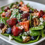 Colorful spinach and berry salad with crumbled goat cheese, toasted walnuts, and homemade honey Dijon dressing.  