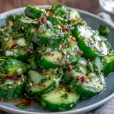 Vibrant cucumber salad with spicy garlic chili oil, scallions, and toasted sesame seeds.  