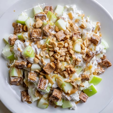 This colorful Snickers Salad showcases chopped Snickers, whipped topping, and apples in every delicious bite.