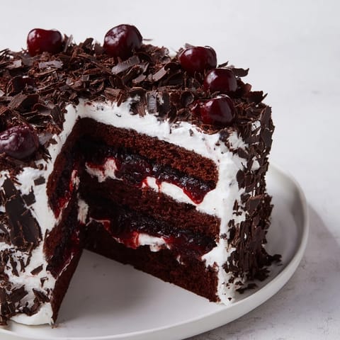 This image displays a beautifully layered Black Forest Cake, rich with decadent chocolate and cherries.