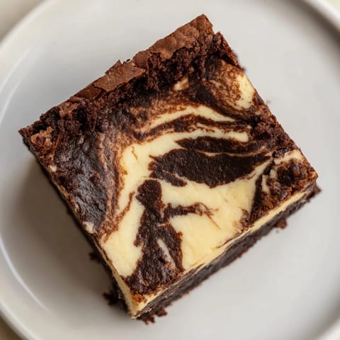 Warm cheesecake brownies with a luscious swirl, offering a rich chocolate and tangy taste experience.
