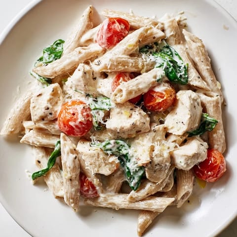 A warm bowl of Greek Yogurt Chicken Pasta, garnished with Parmesan and fresh basil, ready to serve.