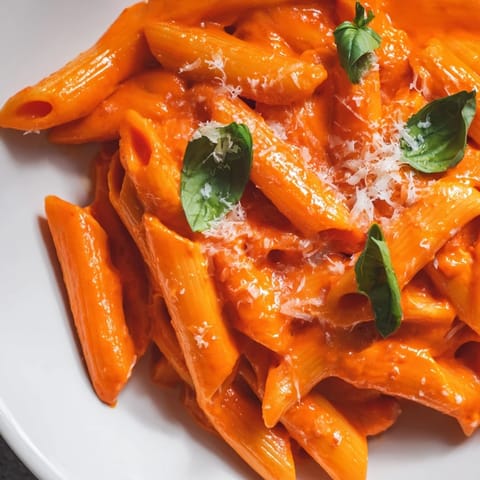 Creamy Roasted Red Pepper Pasta coated in a velvety sauce, ready to serve with Parmesan.