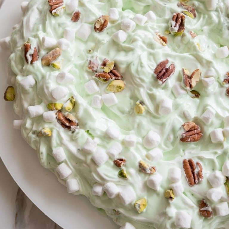 A vibrant bowlful of Watergate Salad, showcasing fluffy whipped topping and refreshing pineapple chunks.