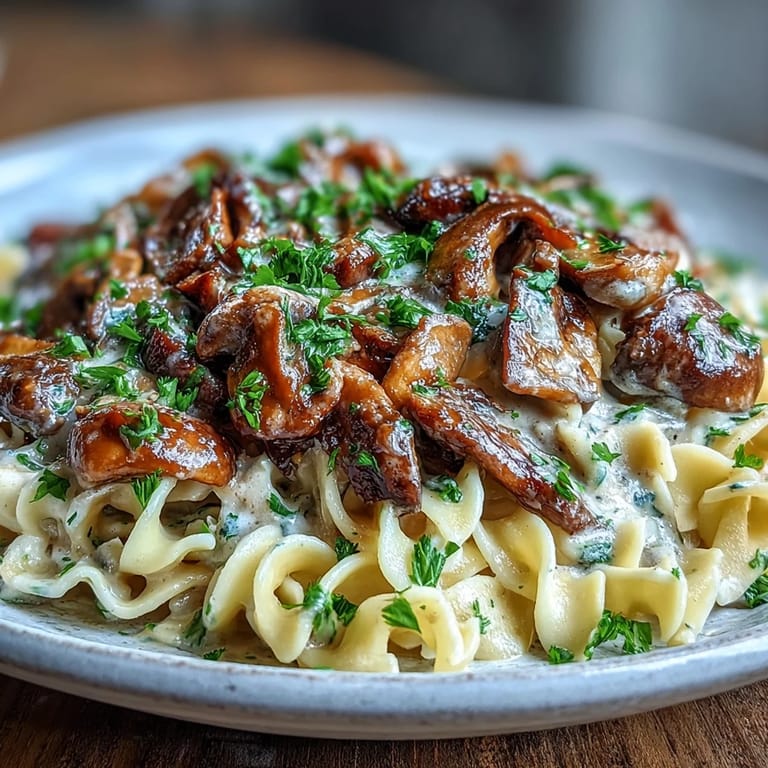 Close-up view of Creamy Mushroom Stroganoff, highlighting the glossy sauce coating noodles and golden-brown sautéed mushrooms.